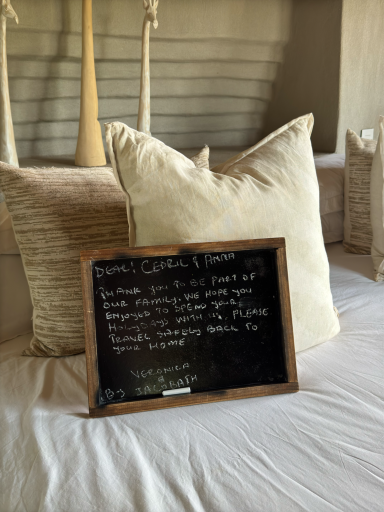 Schwarzes Beschilderung mit weißer Schrift über eine Unterkunft, auf einem Bett mit Kissen.