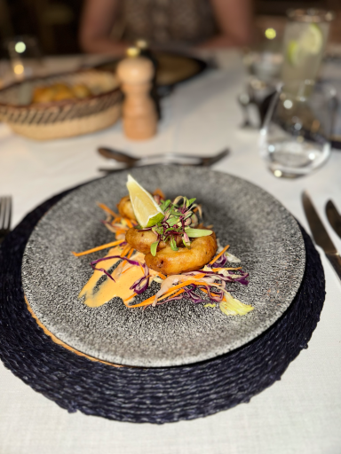 Gegrillte Garnelen mit Gemüse und Limettenschnitz auf einem grauen Teller.