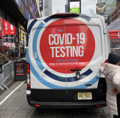Rückseite eines Vans mit Aufschrift "COVID-19 Testing" in einem urbanen Umfeld.