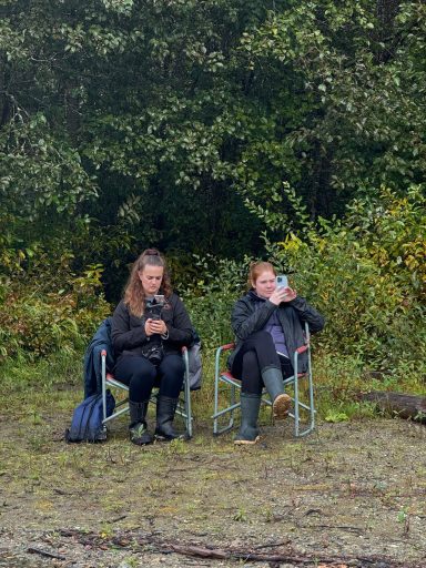 Zwei Personen sitzen in Campingstühlen in einer natürlichen Umgebung.