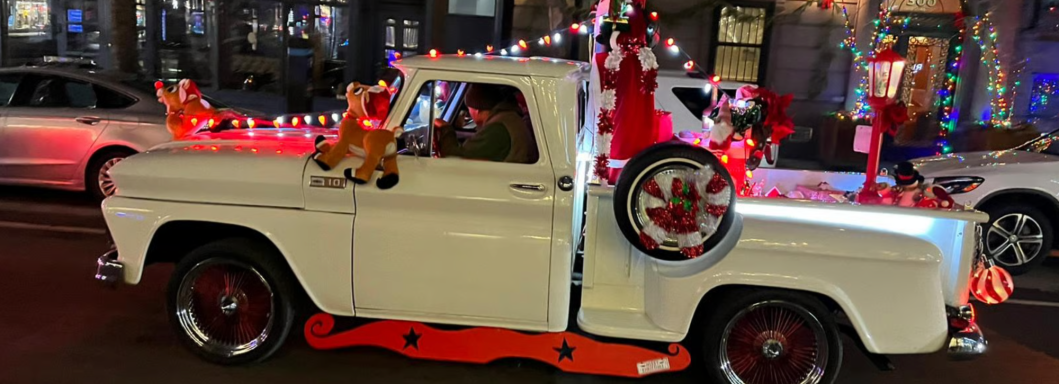 Weißer Pickup mit festlicher Weihnachtsdekoration und Figuren auf der Ladefläche.