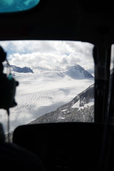 Blick aus einem Hubschrauber auf schneebedeckte Berge und Gletscherlandschaften.