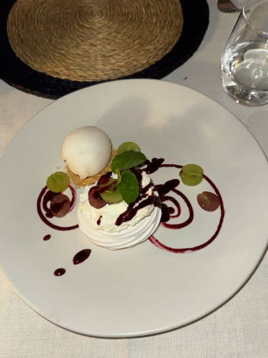 Dessert mit einer Kugel Eis, Sahne, Beerensoße und frischen Kräutern.