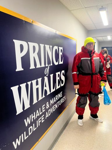 Person in roter Outdoor-Ausrüstung steht neben einem Schild "Prince of Whales".