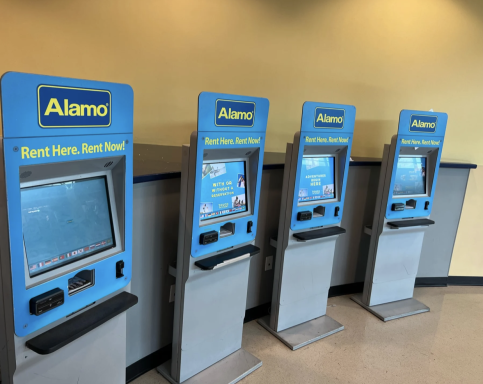 Drei Alamo-Automaten zur Fahrzeuganmietung in einem Empfangsbereich.