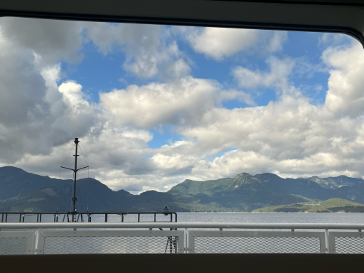 Berglandschaft mit Wolken und Wasseransicht, im Vordergrund ein Steg.
