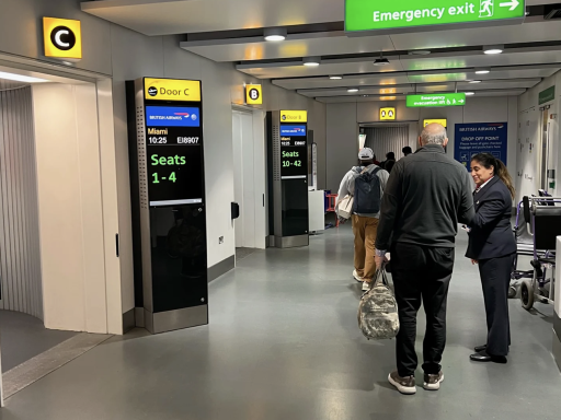 Flughafenbereich mit Informationsanzeigen und Passagieren, die sich in der Warteschlange befinden.