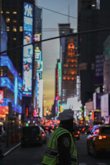 Polizist in Neonlicht von Times Square, lebhafte Stadtatmosphäre bei Dämmerung.