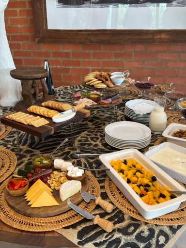 Bunt gedeckter Tisch mit verschiedenen Käse-, Wurst- und Obstplatten sowie Snacks.