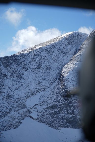 Schneebedeckter Berg mit blauem Himmel und einigen Wolken.