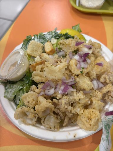 Ein Teller mit frittiertem Gemüse und Salat, garniert mit Zwiebeln und Zitronenscheiben.