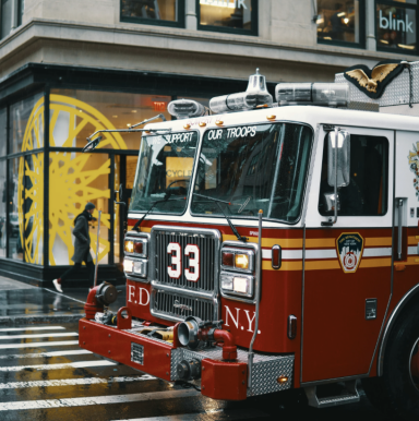 Rotes Feuerwehrfahrzeug mit der Nummer 33 parkt vor einem modernen Geschäft in New York.