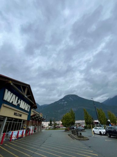 Verregneter Himmel über einem Geschäft in den Bergen. Parkplatz mit Autos im Vordergrund.