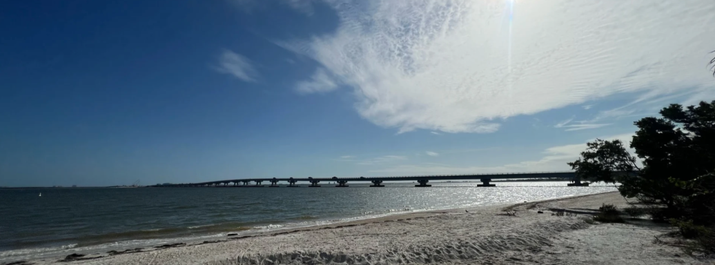 Landschaft mit einer Brücke über das Wasser unter einem klaren, blauen Himmel.