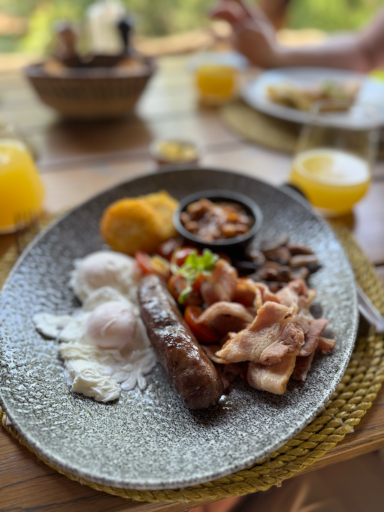 Teller mit Wurst, Schinken, Bohnen, Reis und einer Beilage, serviert mit Getränken.