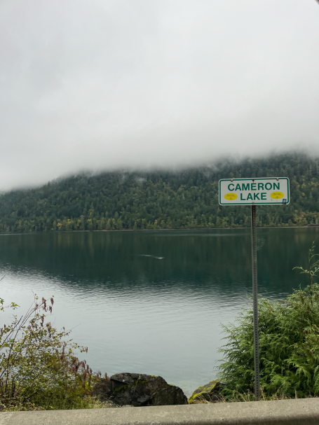Schilder mit der Aufschrift „Crescent Lake“ vor einem ruhigen, bewölkten See.