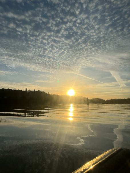 Sonnenuntergang über einem ruhigen Gewässer mit Wolkenhimmel und reflektierendem Licht.