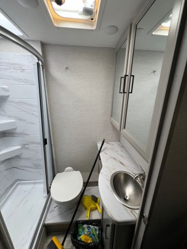 Kleines Badezimmer mit Dusche, Toilette und Waschbecken, hell mit Fensterausschnitt.