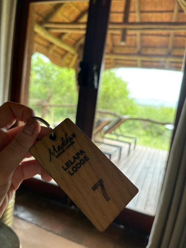 Holzschlüsselanhänger mit der Nummer 7, Blick auf eine Terrasse und grüne Landschaft.