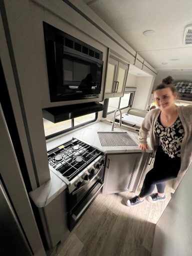 Moderne Küchenzeile in einem Wohnmobil mit Person, die neben dem Herd steht.