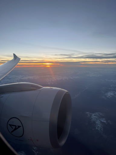 Sonnenuntergang über den Wolken mit Flugzeugtriebwerk im Vordergrund.