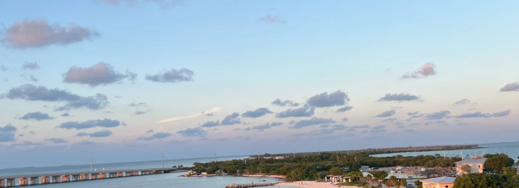 Himmel über einer Küstenlandschaft mit Wolken und calmem Wasser.