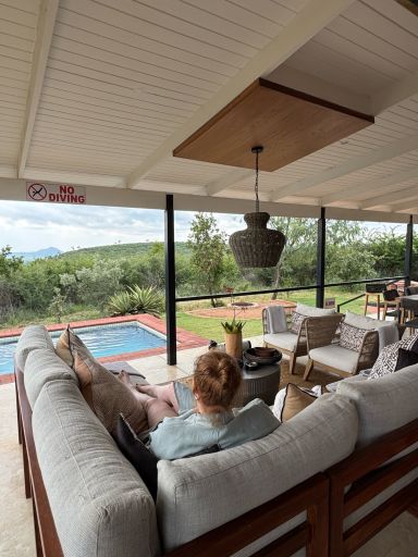 Gemütlicher Sitzbereich mit Blick auf den Pool und die Landschaft. Frau sitzt entspannt.