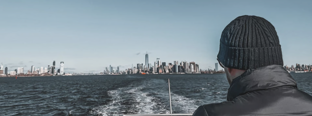 Person in einem Boot blickt auf die Skyline einer Stadt am Wasser.