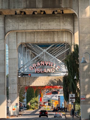 Sicht auf das Granville Island-Schild unter einer Brücke, umgeben von Bäumen und Straßen.