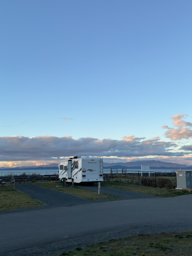 Wohnmobil befindet sich auf einem Parkplatz mit Weitblick in eine bewölkte Landschaft.